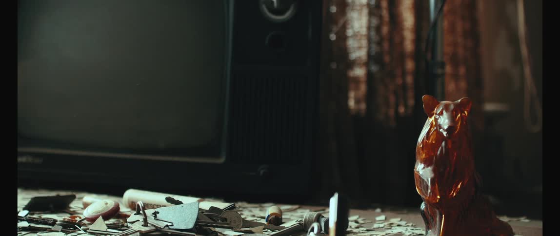 Vintage television on top of a surface with a crystal doll next to it and abstract broken things