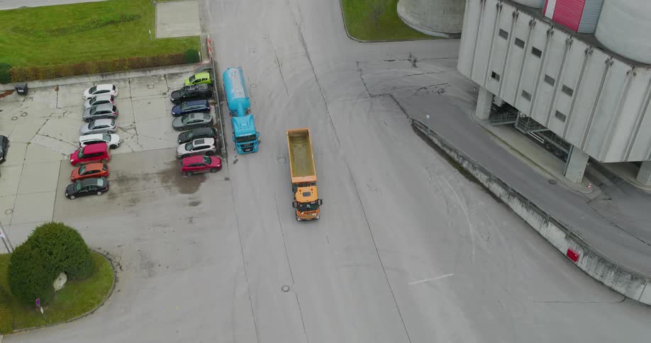 An aerial clip of a yellow truck moving along the road of an industry