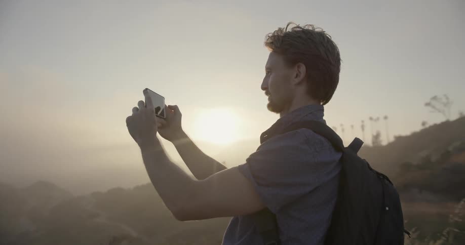 A man standing on the edge of a mountain and taking photographs