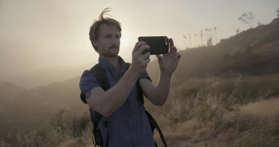A man is standing on the side of a hill taking a photo