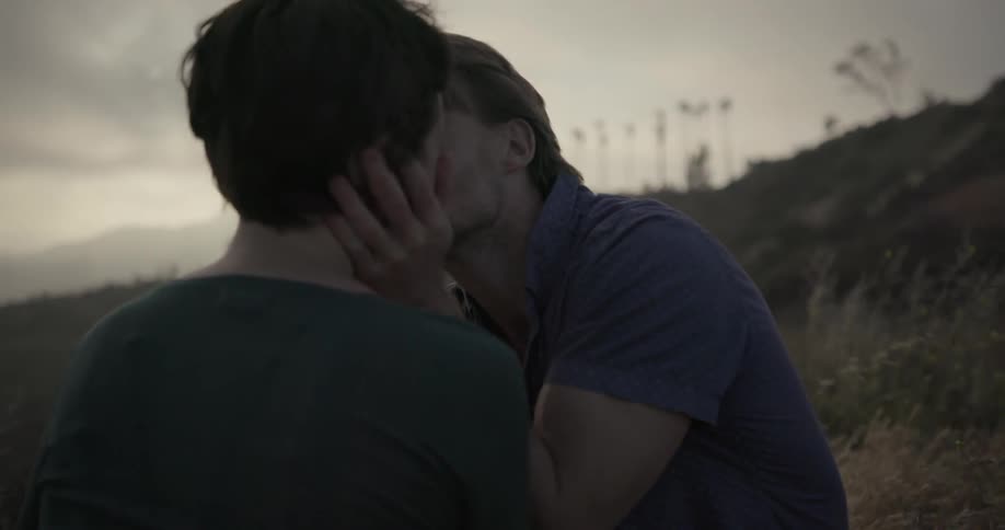 A man and woman kiss outside on an overcast day