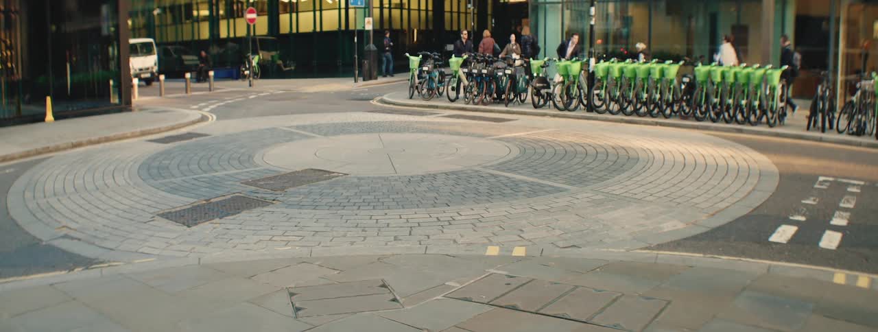 Pedestrians and other people on bicycles walk along a street in a metropolis