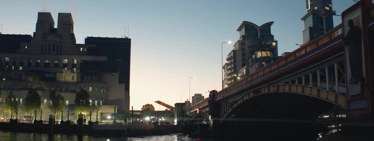 Vauxhall bridge in london is shown at twilight with the river thames flowing beneath and the illuminated buildings of the cityscape in the background