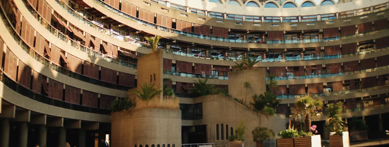 Campus with modern and circular architecture and an urban building in the background
