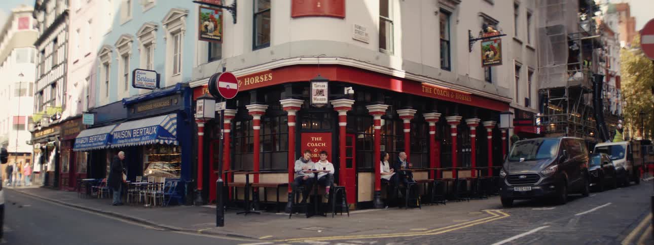 People sitting at tables outside a corner bar