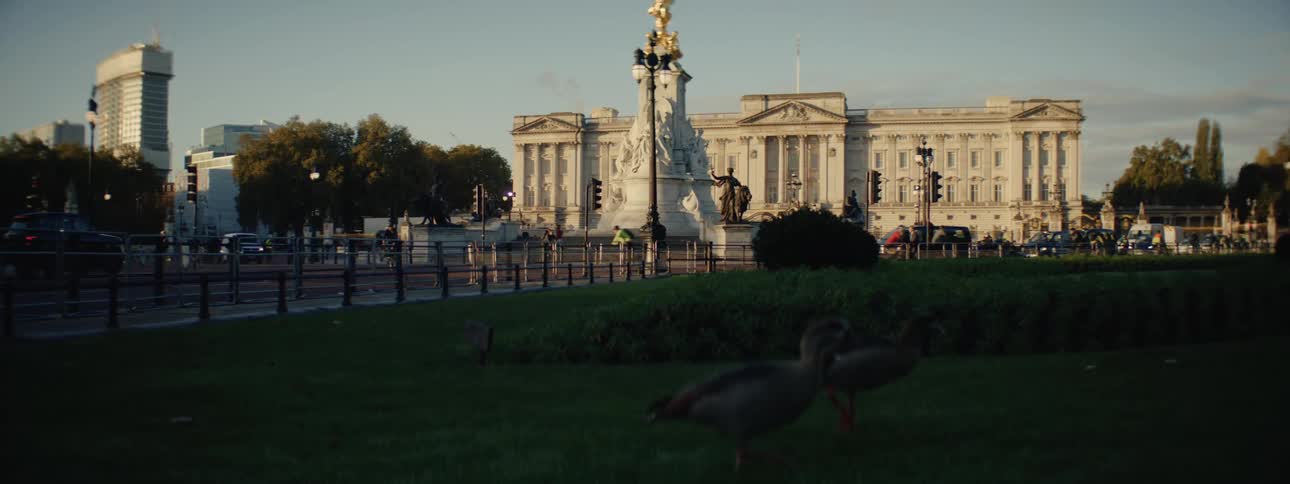 Urban landscape with pedestrians and cars and in the background a statue in a classical palace