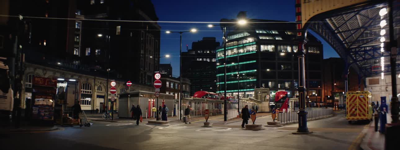 People walking at night next to a station in a metropolis