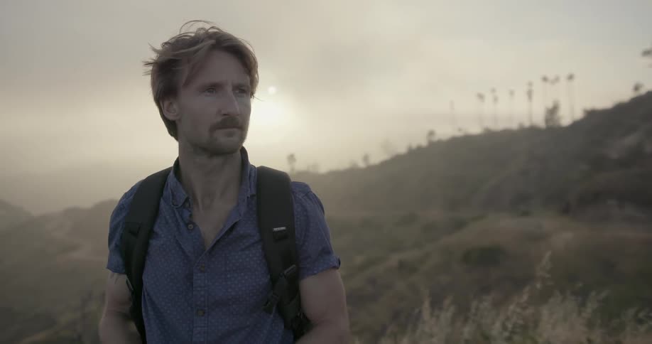 A man stares out from atop a hill and takes a photograph