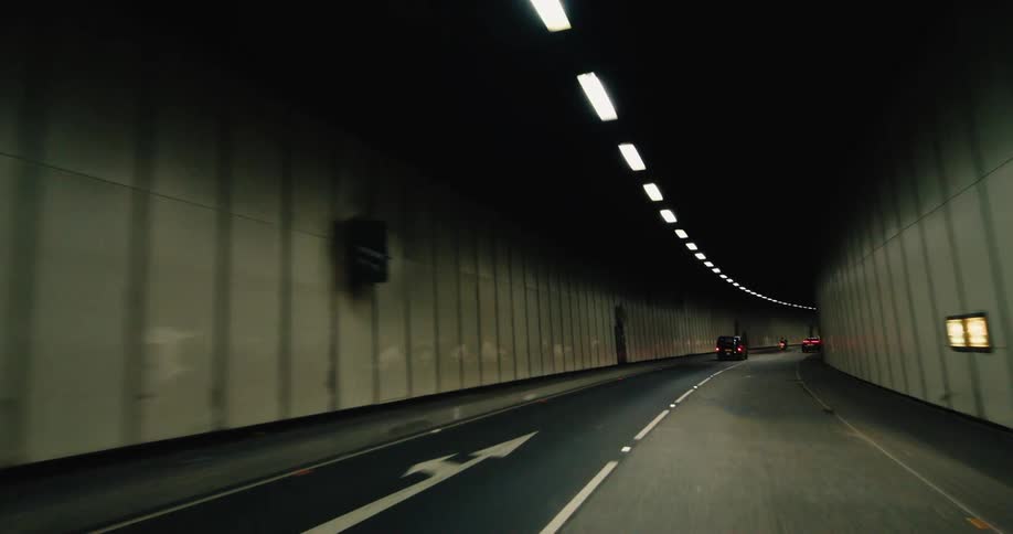 The interior of a well lit tunnel with cars driving through it