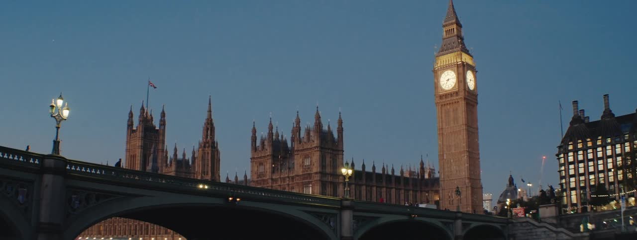 Big ben illuminated against a twilight sky with the houses of parliament and westminster bridge in the foreground