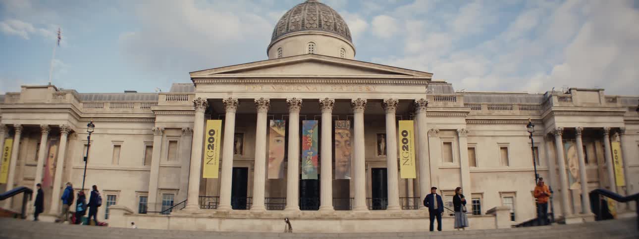Building with classical architecture and a dome in front with people walking
