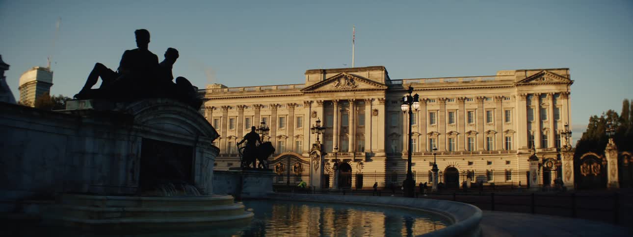 Landscape of an artistic fountain in front of a classical building with the silhouettes of people walking