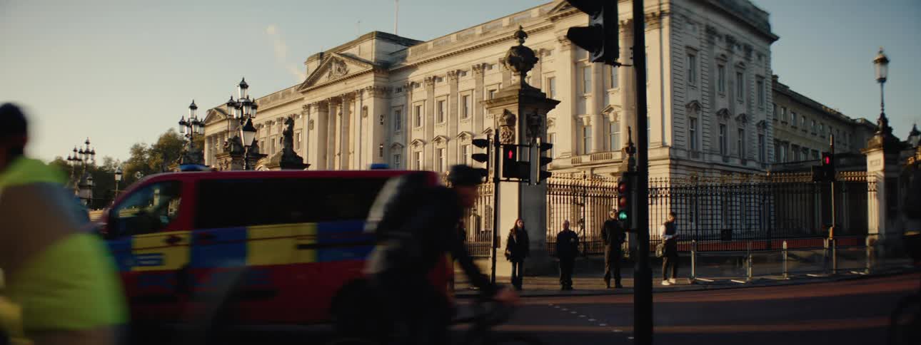 Busy street with vehicles and pedestrians and the british royal building in the background