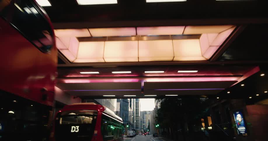 Street in a busy metropolis with a bus stopped below a viaduct with a train crossing