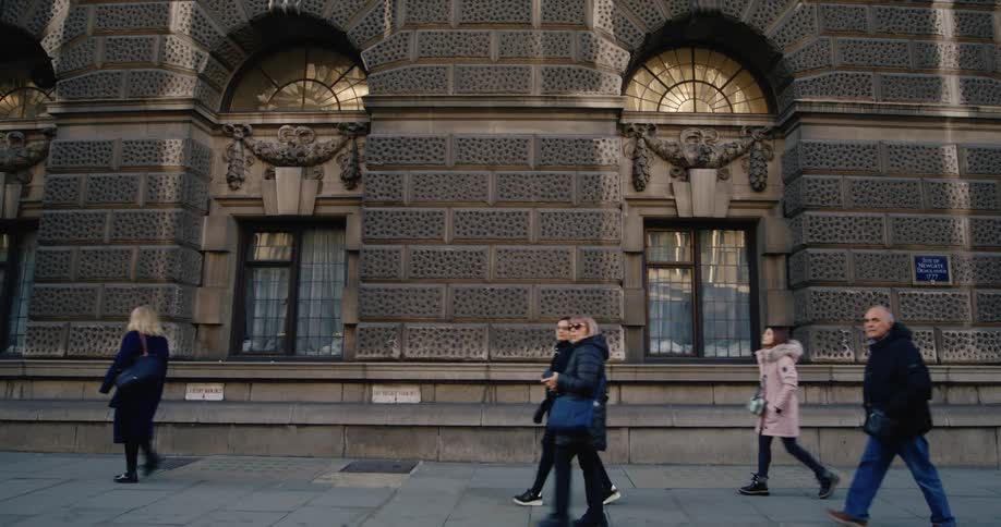 People walking on the sidewalk next to a classic building