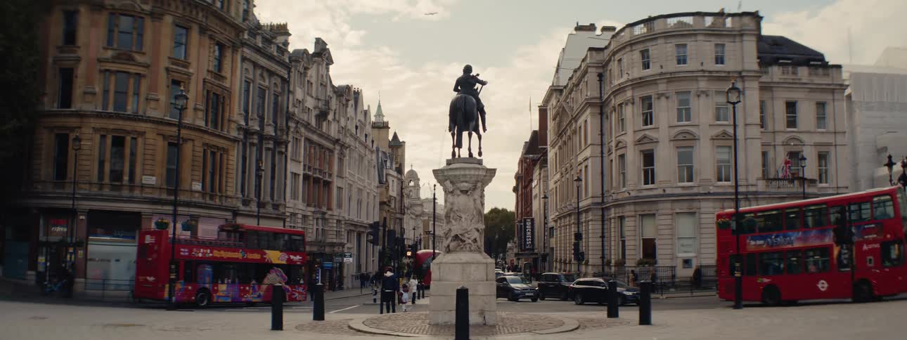 Square with a classical statue next to streets and intersections in a metropolis with vehicular and pedestrian traffic