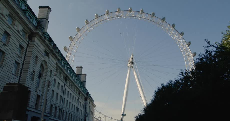 Ferris wheel next to a classic british building
