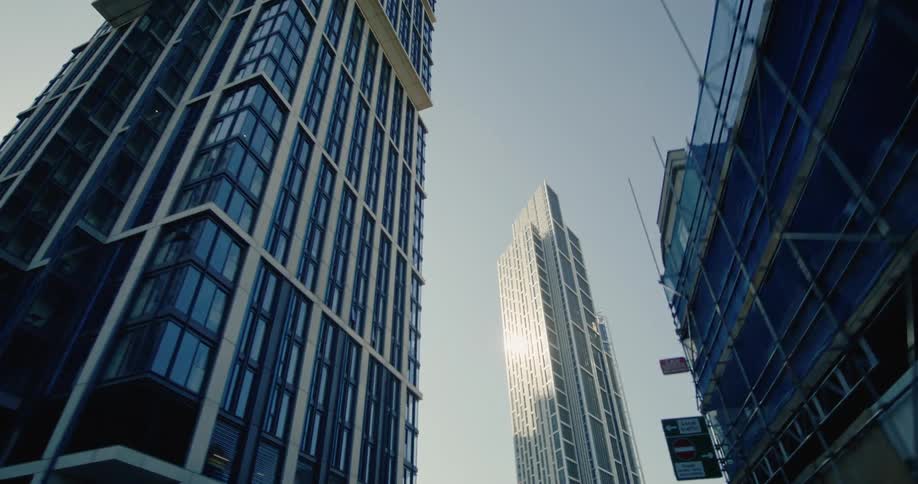 A low angle view of several modern skyscrapers against a pale sky emphasizing their height and architectural lines