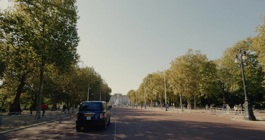 Street with vehicle traffic and trees around with sidewalks and people walking