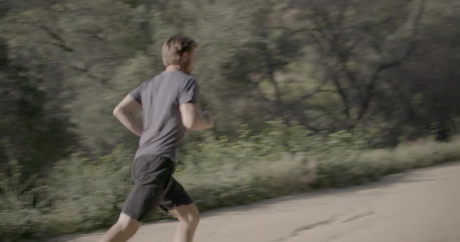A man jogs in a shrubby and rural area