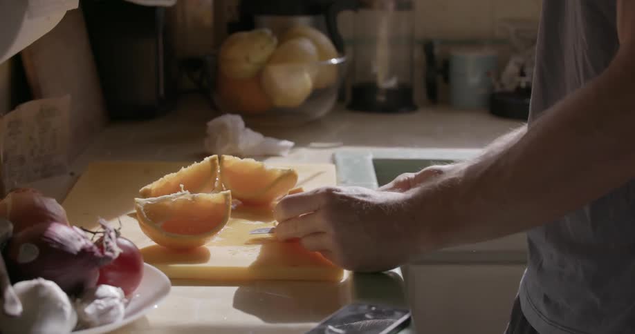 A man is cutting some fruit on a counter