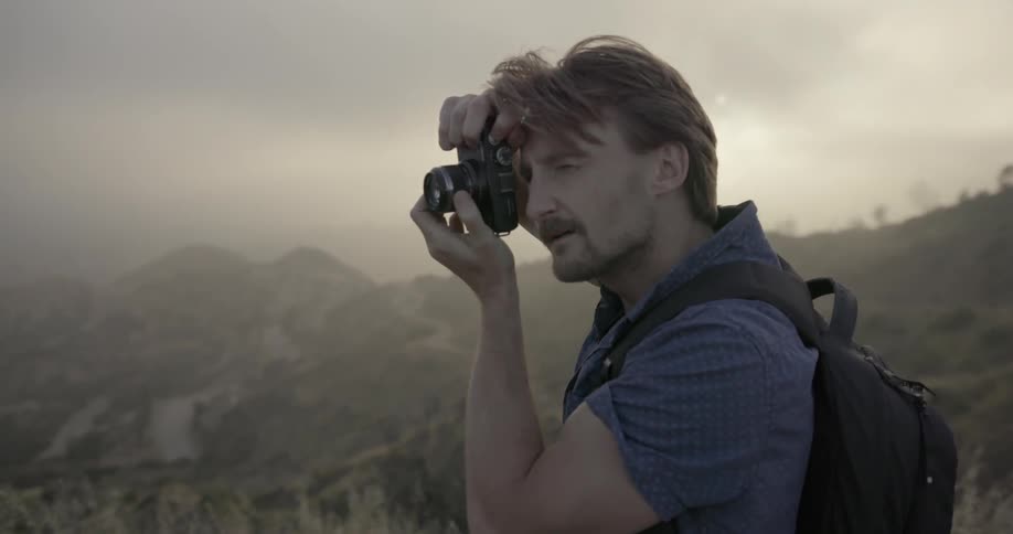 A photographer takes a photograph from atop a mountain