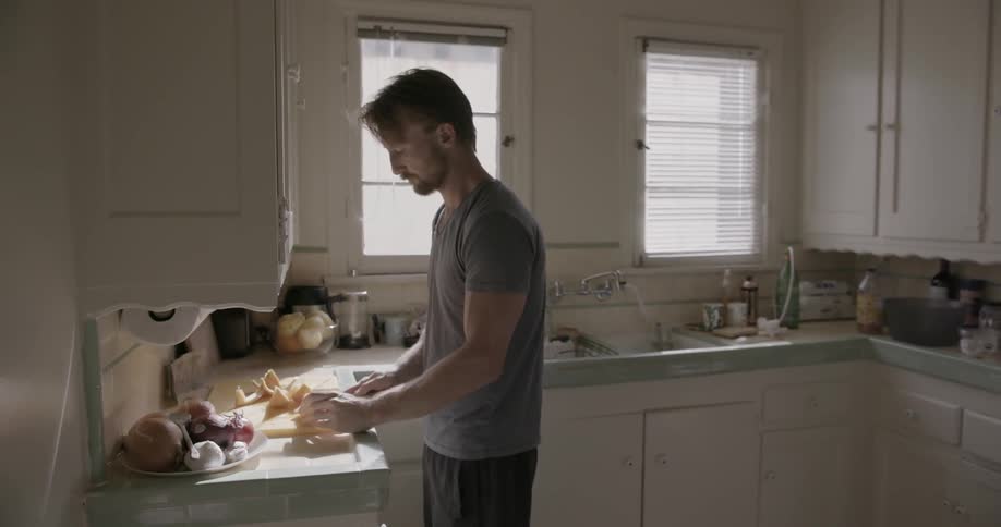 A man is preparing a meal in a kitchen during the day