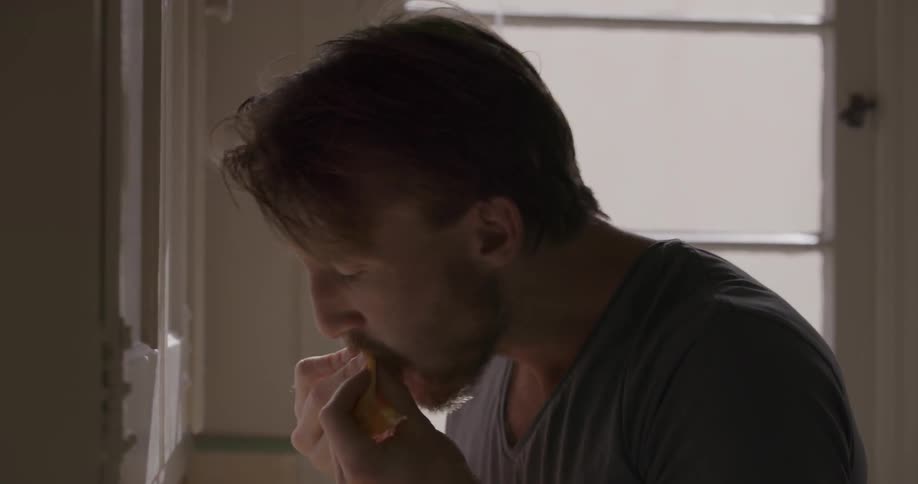 A man takes a bite of food in the kitchen