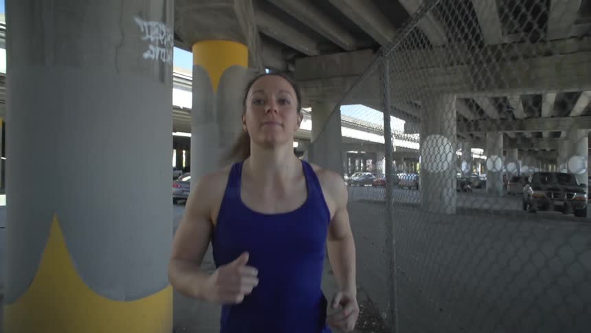 Woman jogging under a bridge