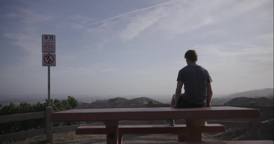 A man is sitting on a table near a sign