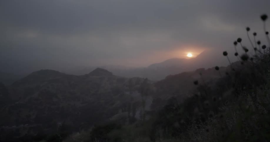 The sun is setting behind the mountains in the distance