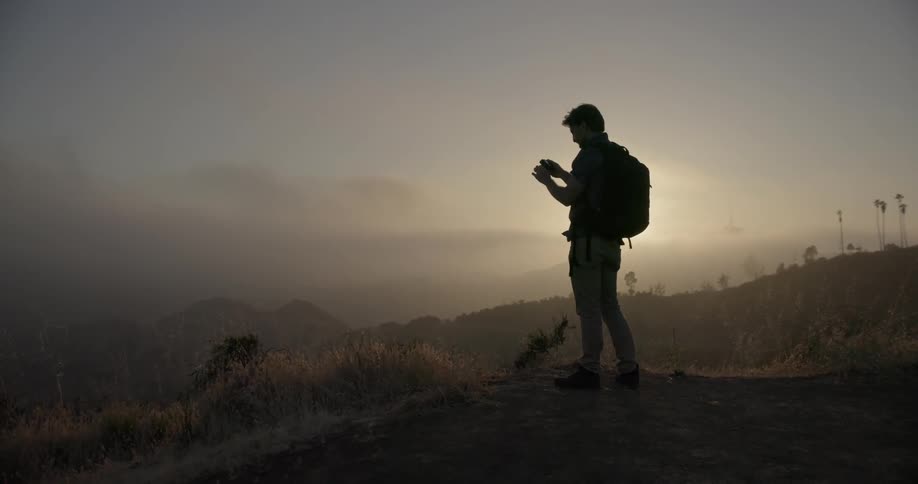 A hiker takes a photograph overlooking a valley