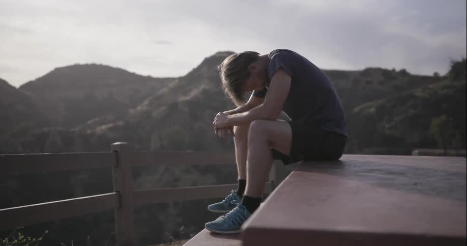 A man sits with his head down on top of a picnic table
