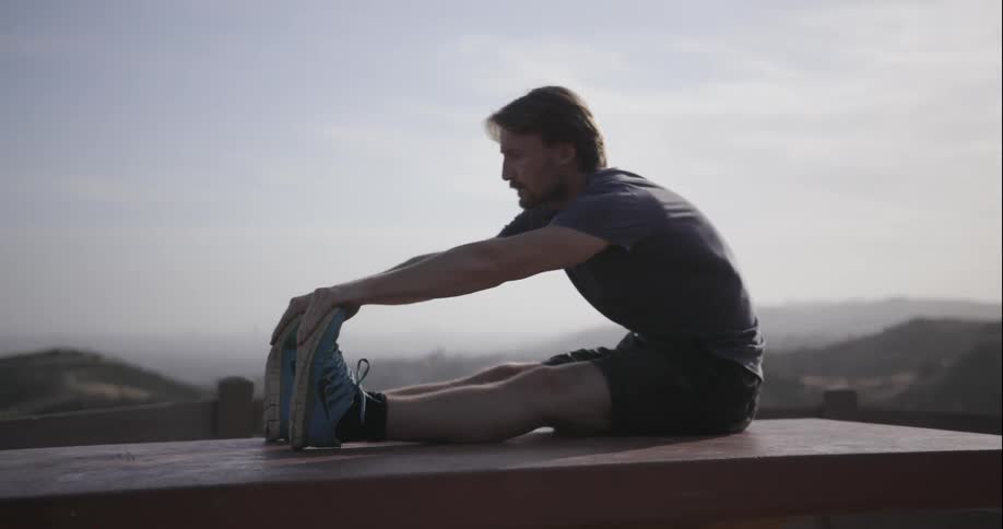 Man sitting down leans forward and stretches legs