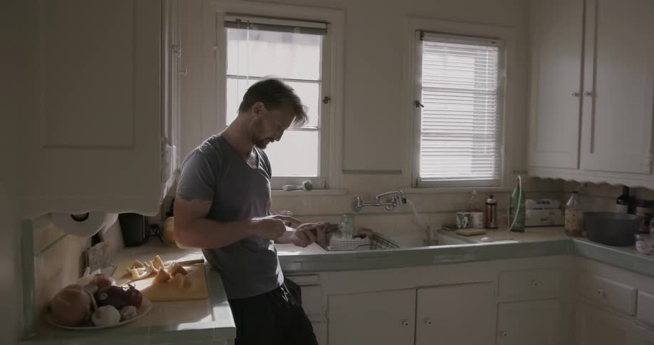 A man uses his phone in the kitchen