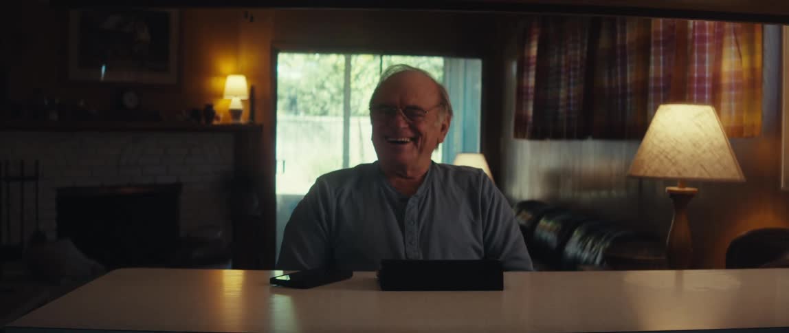 A man is sitting at home laughing