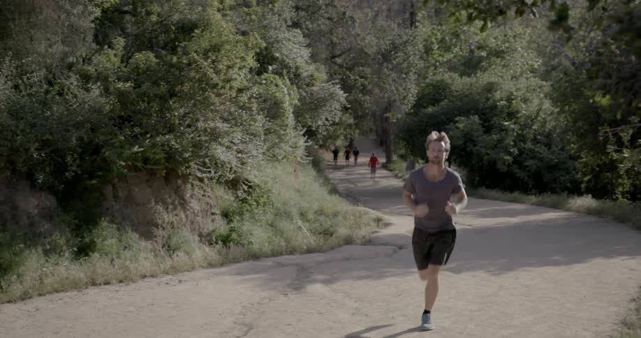 A man is running along the road while people stand in the background