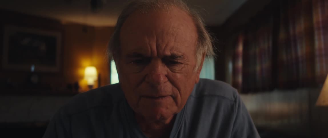 An elderly man is sitting down using a tablet and then he becomes astonished and takes off his glasses and starts smiling