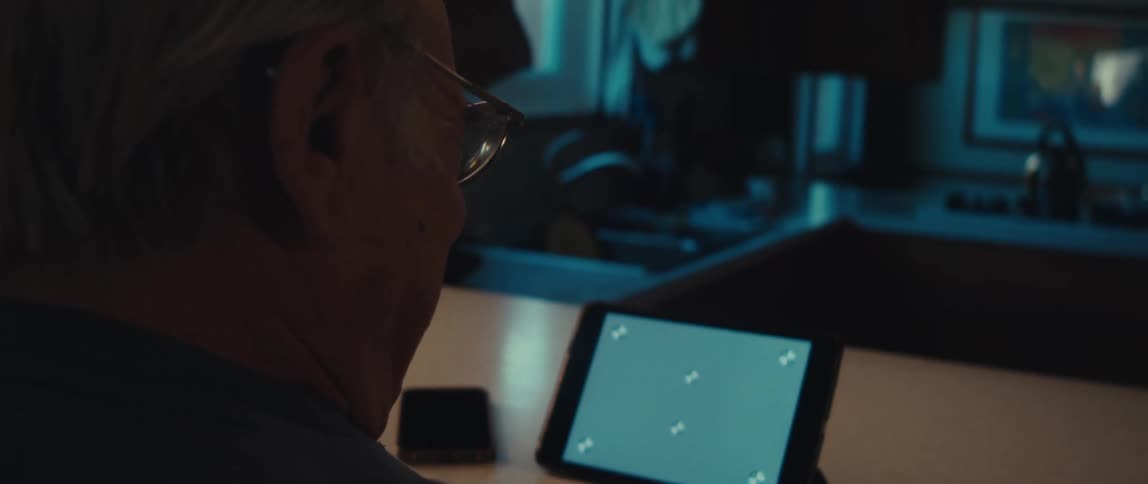 Elderly man sitting interacting in front of a tablet