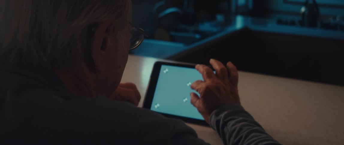 Elderly man sitting interacting with tablet on top of table