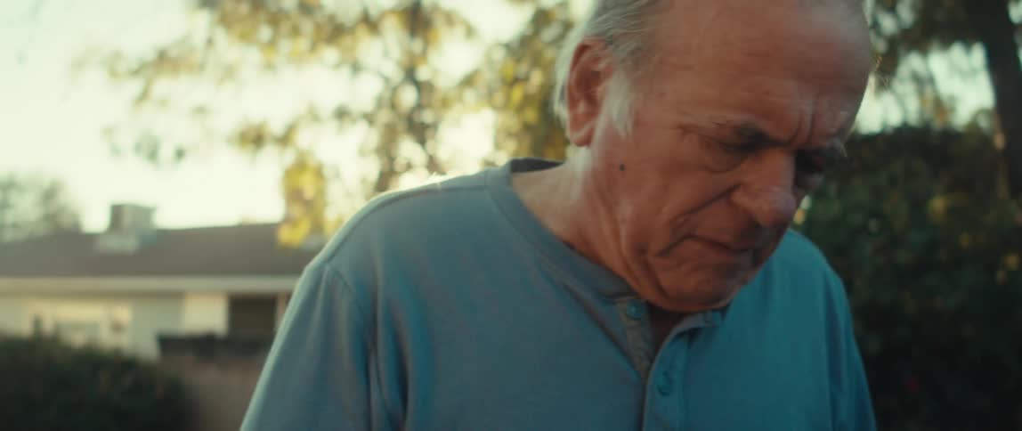 Elderly man walking through backyard with a smartphone