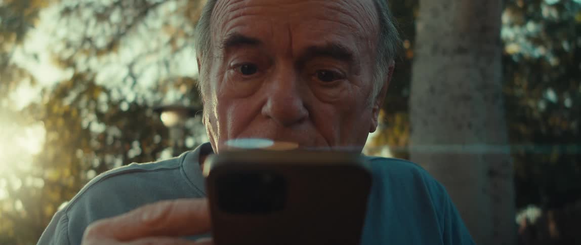 Man sitting outdoors and contemplating while he texts on a cellphone