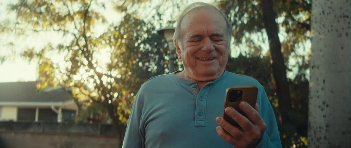 Happy senior man while outdoors interacting with smartphone