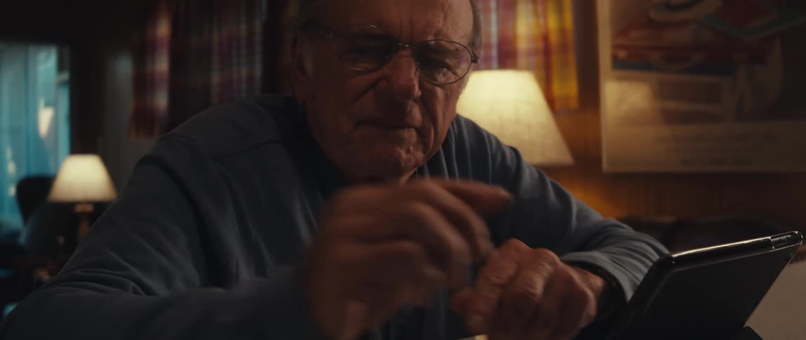 Elderly man sitting interacting with tablet and smartphone