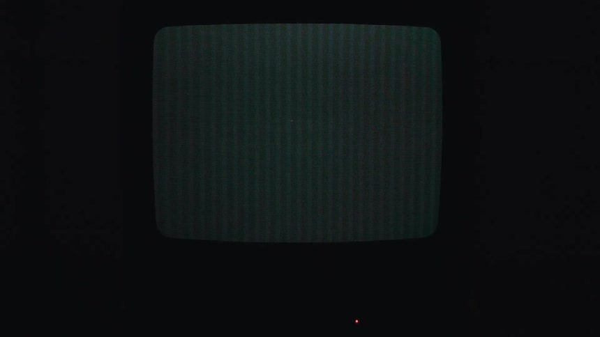 An old television with a black screen flashing white text and then red