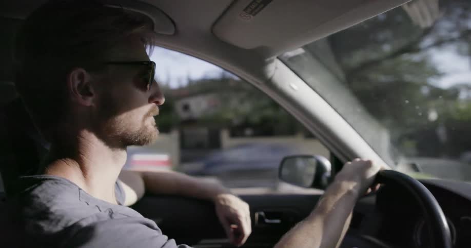 A man is driving a car wearing sunglasses