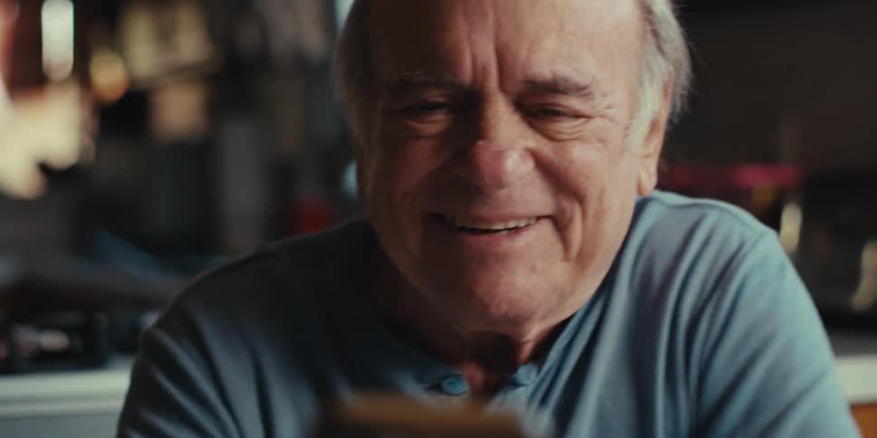 Cheerful elderly man walking around the house holding a smartphone