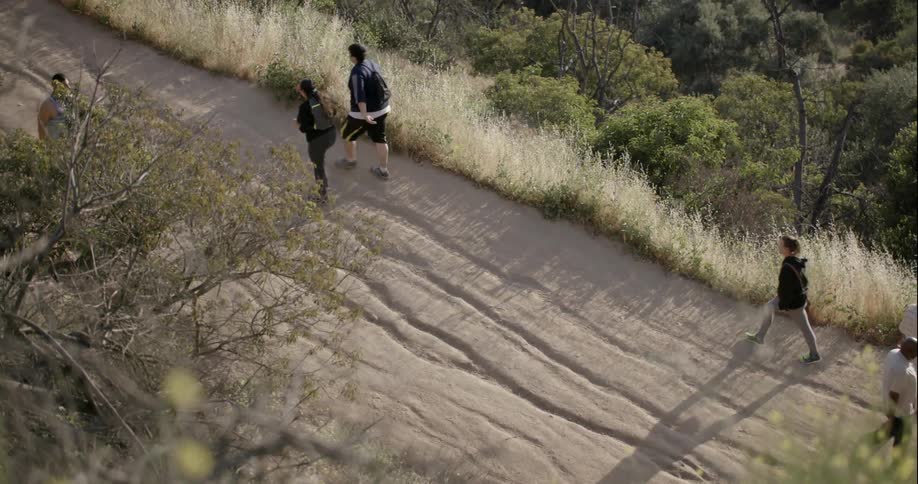A jogger runs up a hill while people hike