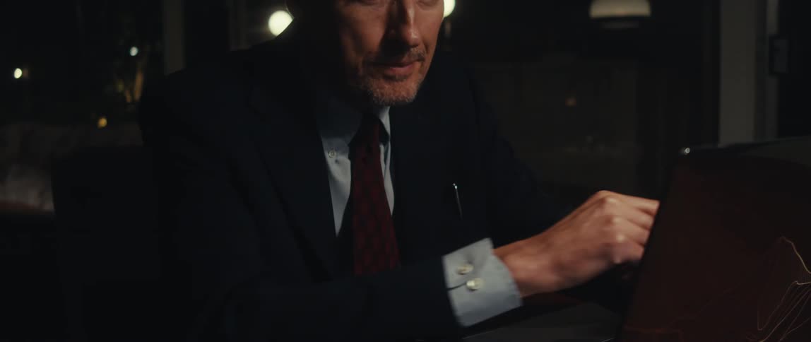 Man in suit sitting typing on a laptop