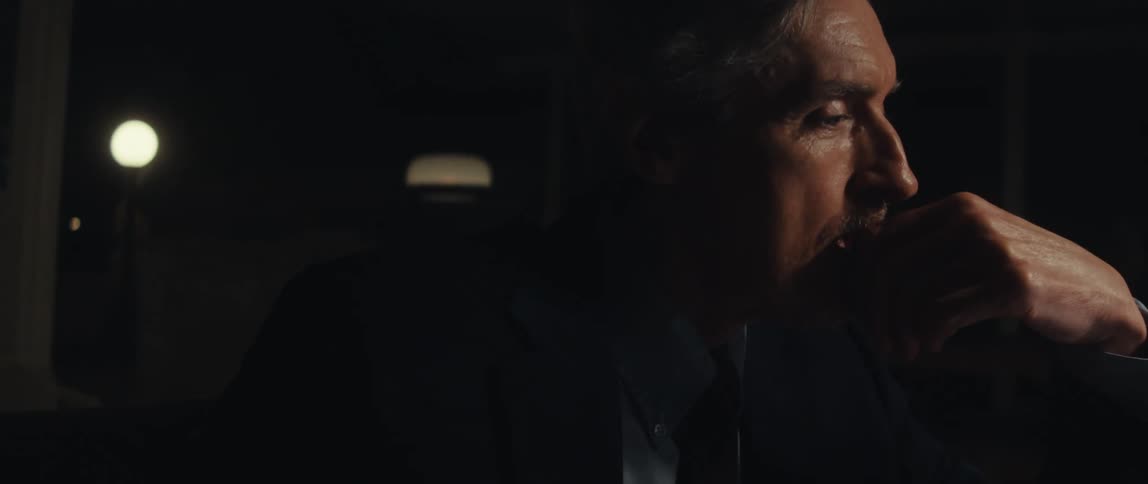 Man in suit sitting in a room at night